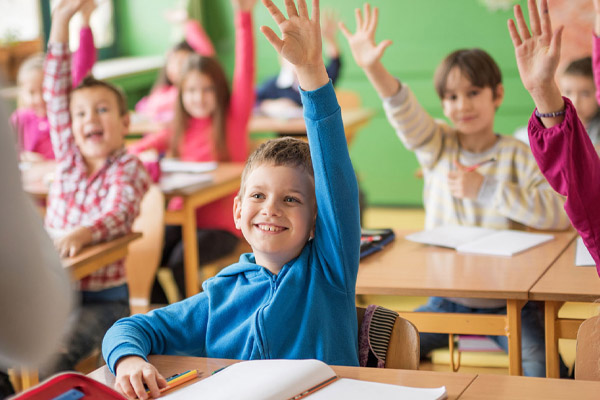 Kinder in Österreichen sitzen in einer Schulklasse und zeigen auf